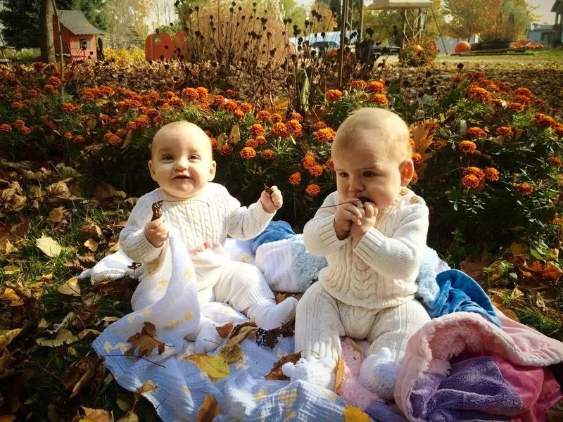 Two babies sitting among autumn leaves and marigolds, a past photo contest favourite