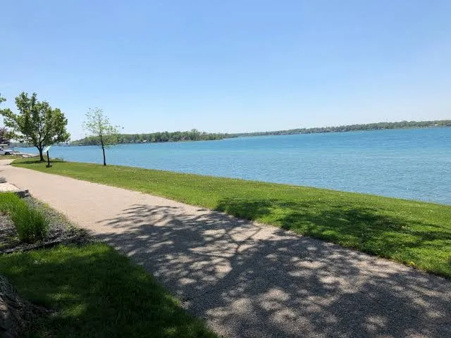 A paved stretch of the St. Clair River Trail beside the blue water of the river