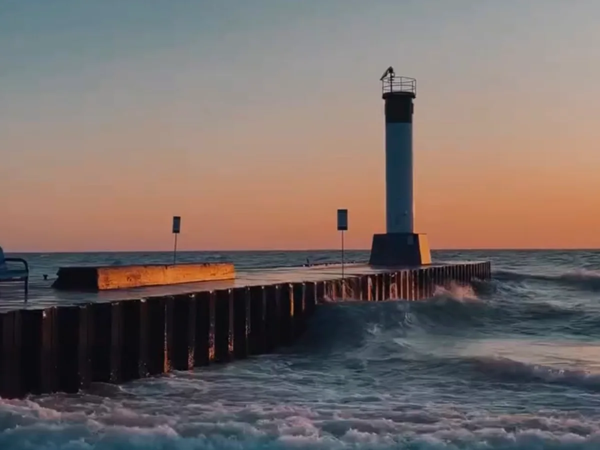 Waves breaking against the Grand Bend pier beneath the lighthouse at sunset