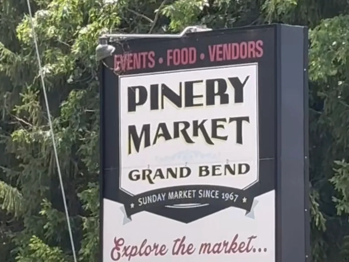 The Pinery Market sign at the roadside under the trees: events, food, vendors, Sundays 9 to 4