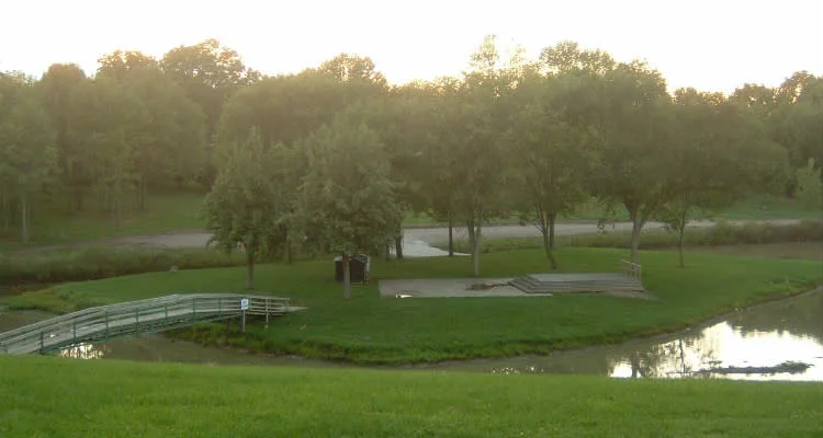 The pond, footbridge and paved amphitheatre stage at Esli Dodge Conservation Area in Forest, seen at dusk