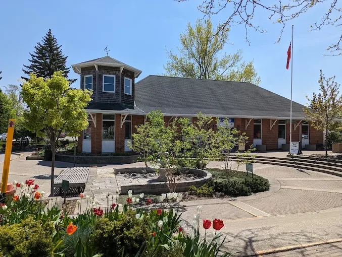 Forest Library, a brick building with a shingled corner tower recalling the town's old railway station, with tulips blooming in front