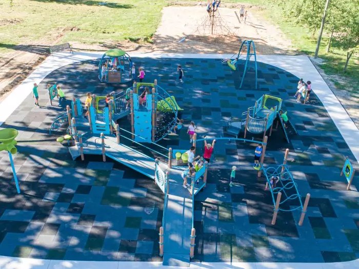 An aerial view of Greenwood Park's accessible playground, with a poured rubber surface and children playing