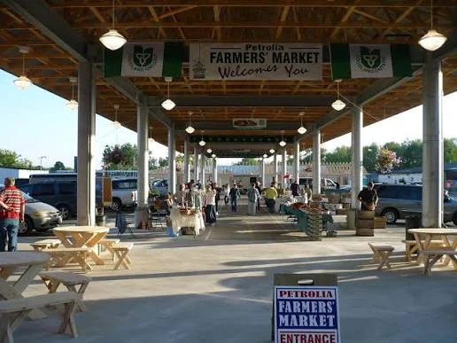 The covered pavilion of the Petrolia Farmers' Market with picnic tables and a welcome banner