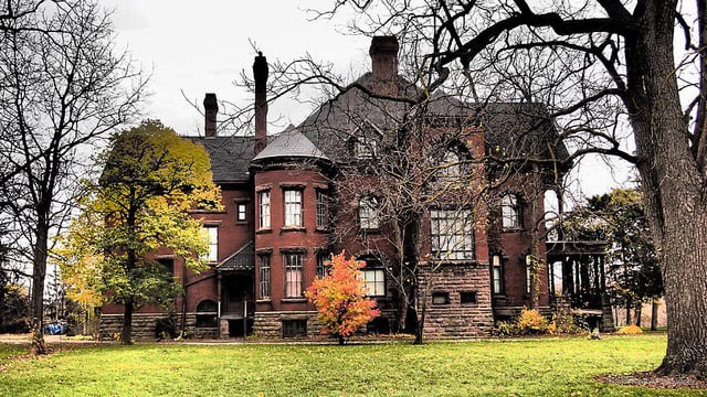 Sunnyside, the Fairbank House in Petrolia: a red-brick Victorian mansion with a turret, tall chimneys and a stone foundation among bare autumn trees