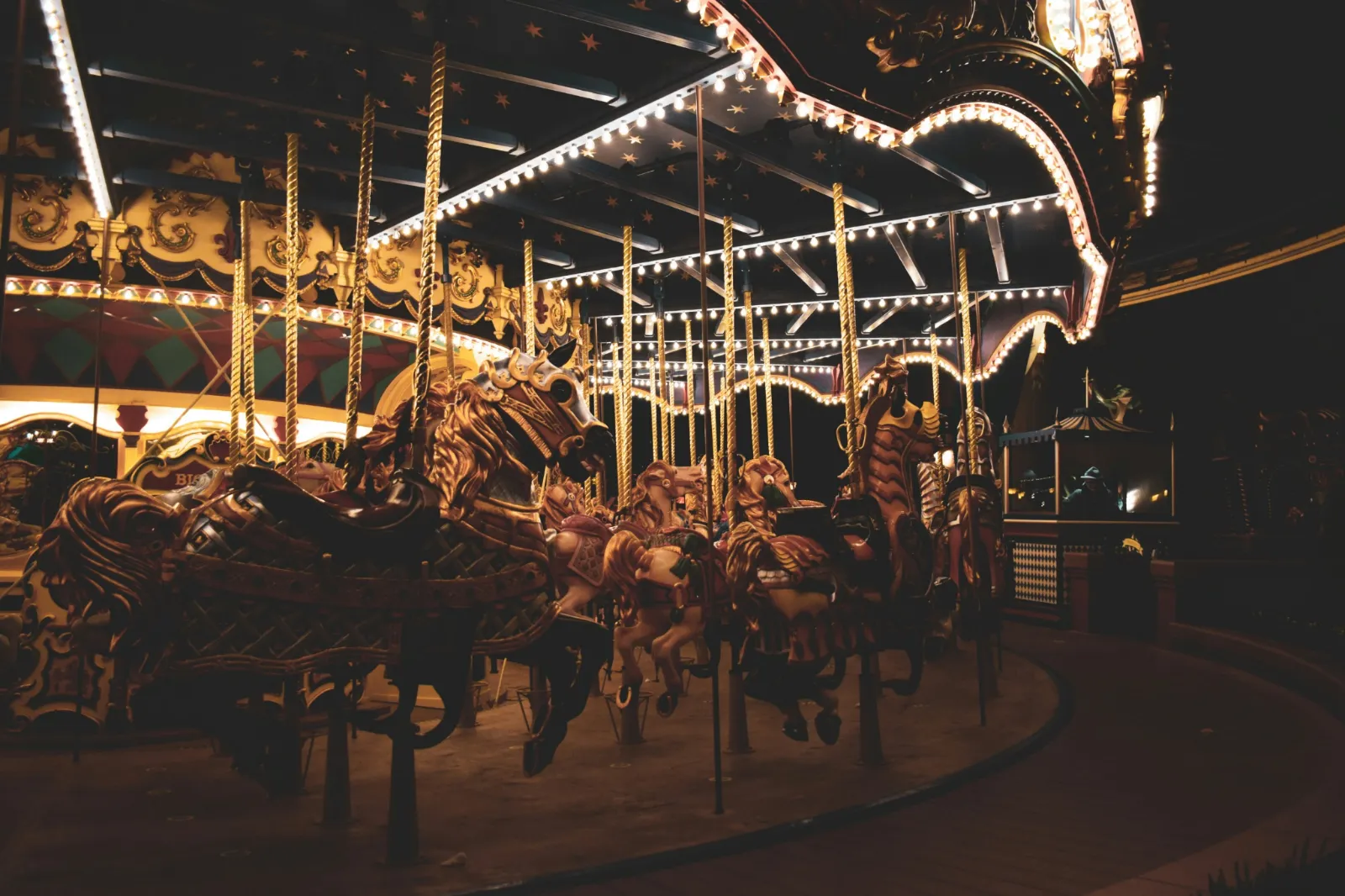 Carousel horses beneath warm fairground lights at night