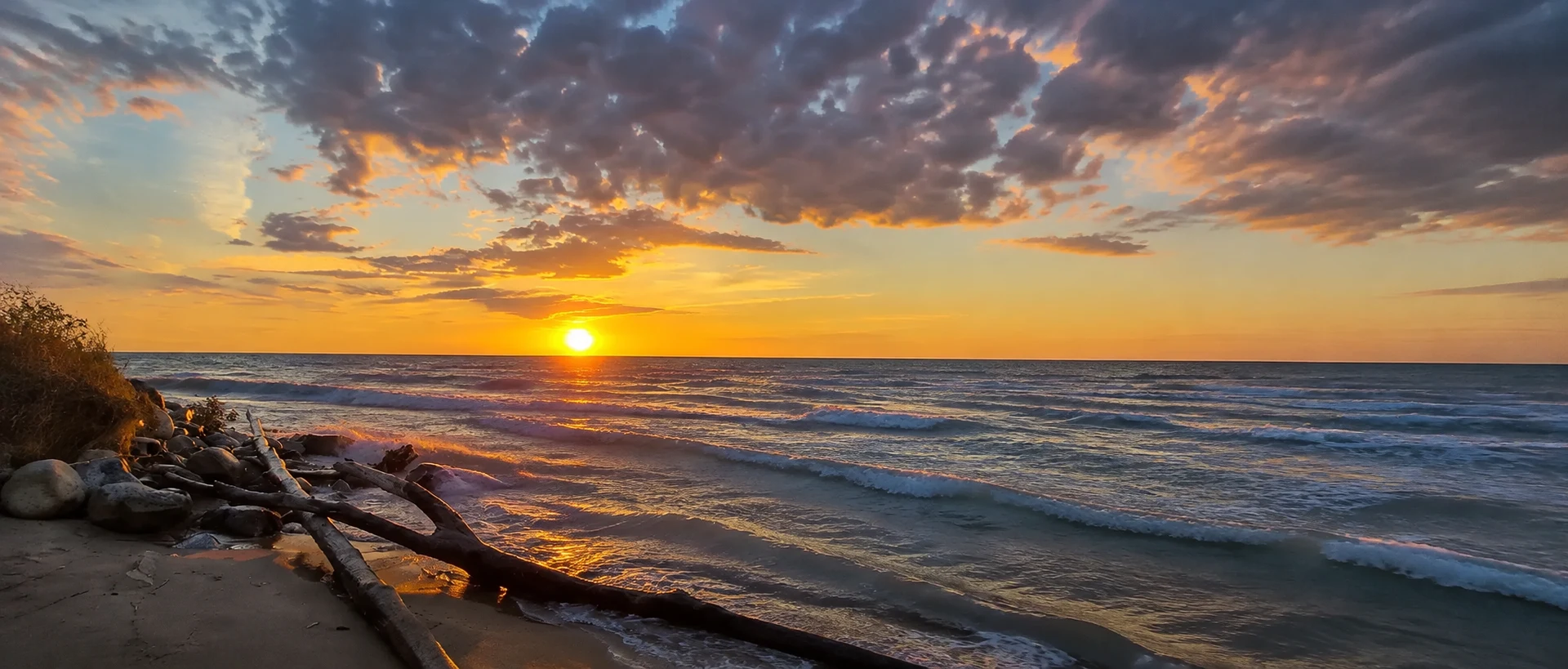 Sunset over Lake Huron from the beach at Grand Bend, with driftwood in the foreground