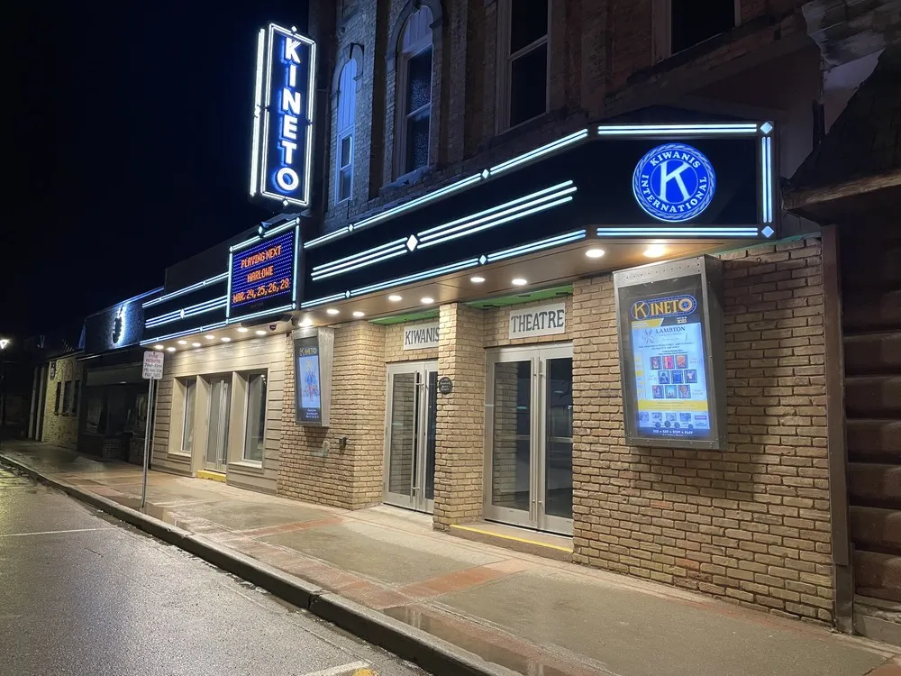 The Kineto Theatre at night, its blue neon sign and lit marquee above the brick front on King Street West in Forest