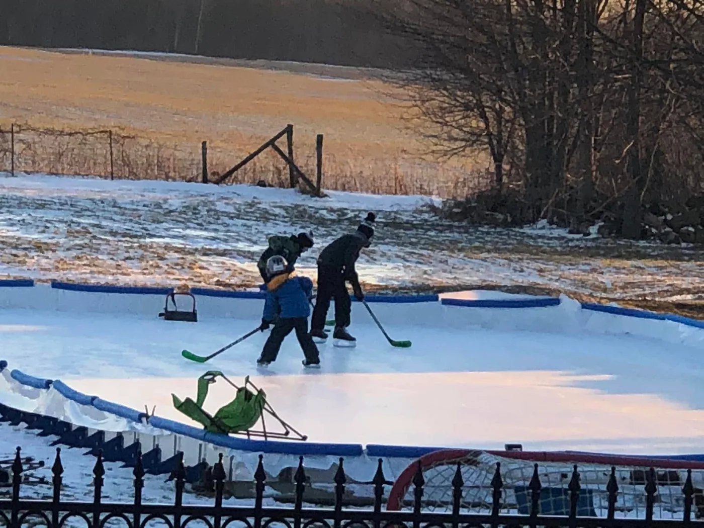 Children playing hockey on a boarded outdoor rink in the low winter sun