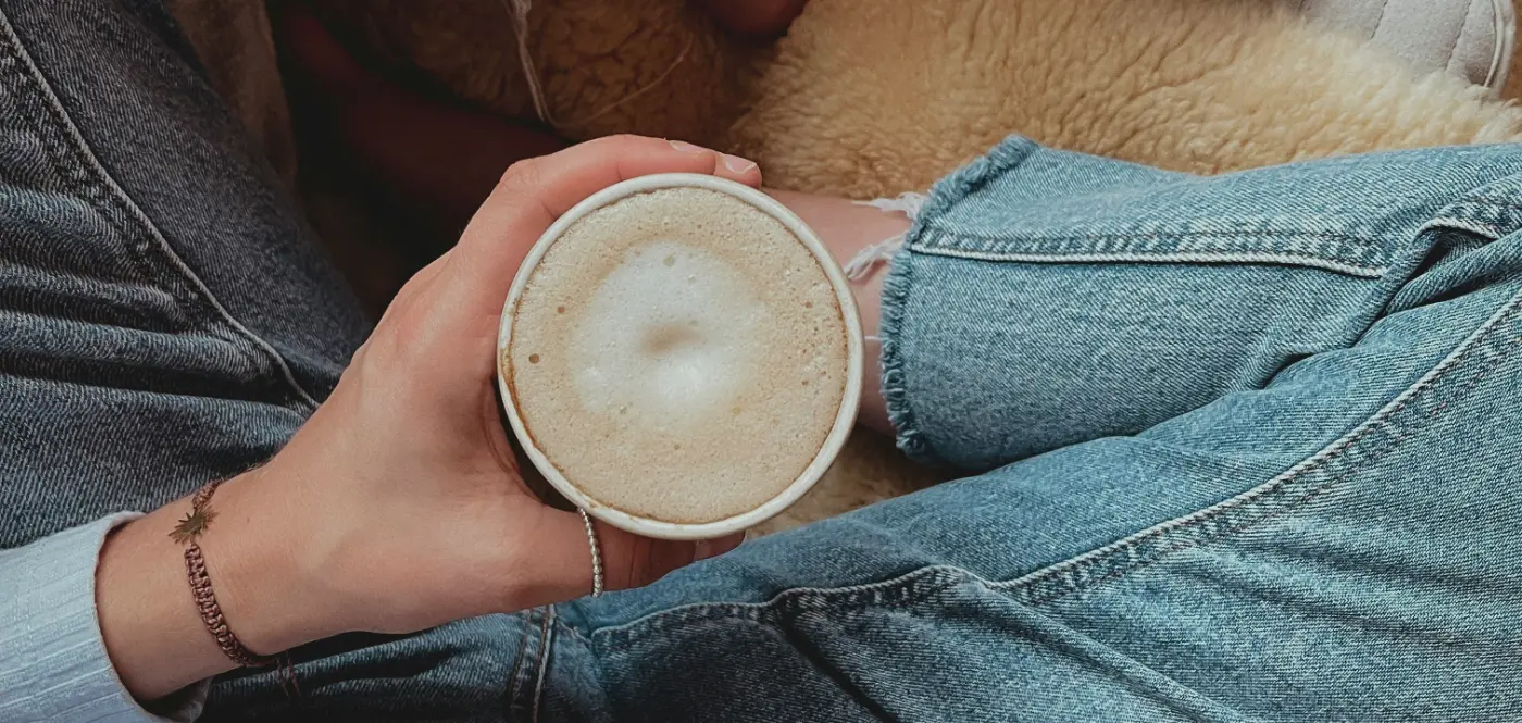 Curled up in a sheepskin chair with both hands round a frothy mug