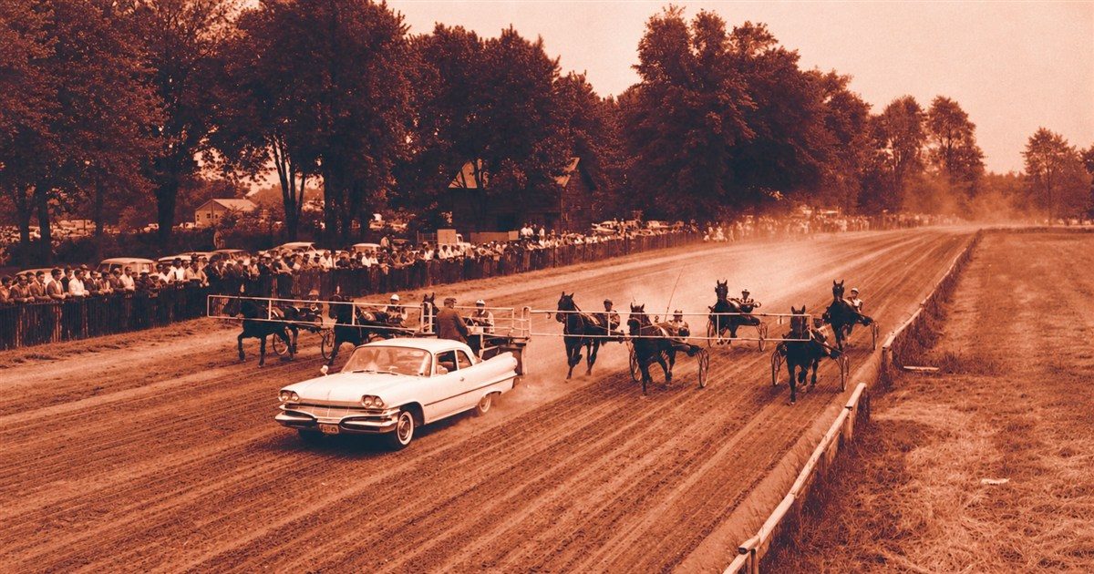 A sepia photograph of harness racers and a pace car on the track at the Petrolia fairgrounds