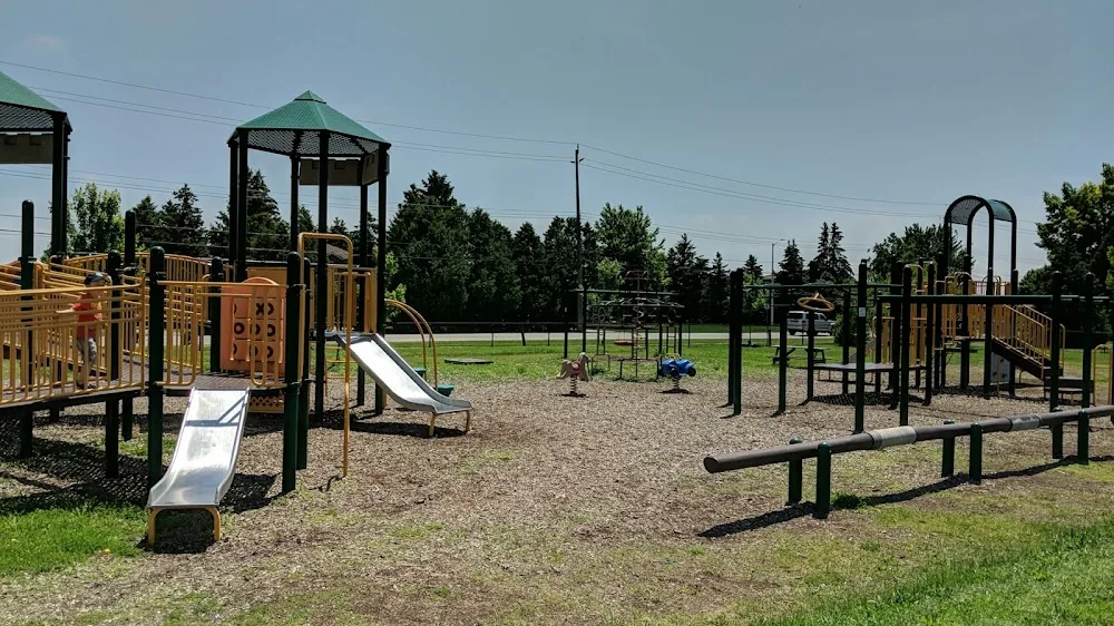 The wood-toned play structures, slides and monkey bars at Blackwell Park in Sarnia, set on wood chips beside open sports fields