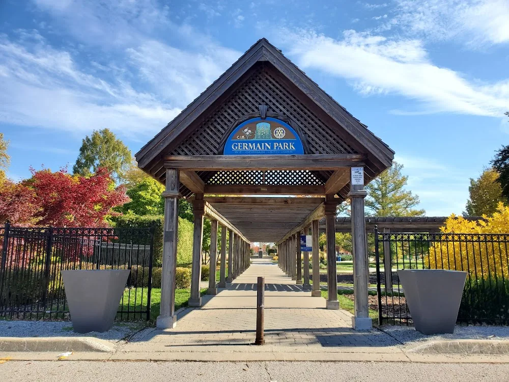 The covered wooden entrance archway and sign at Germain Park in Sarnia, with the garden walkway leading into the park